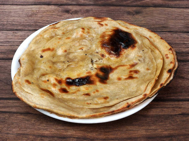 Lachha Paratha, a layered flat bread using wheat flour, popular dish in north India. isolated over a rustic wooden background, selective focus Lachha Paratha, a layered flat bread using wheat flour, popular dish in north India. isolated over a rustic wooden background, selective focus ghee stock pictures, royalty-free photos & images