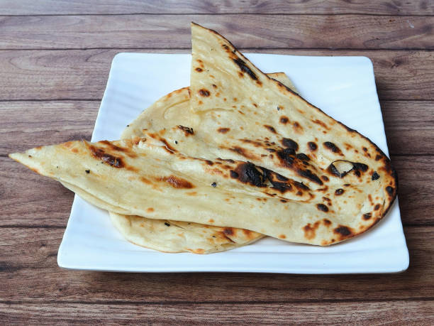 istock Butter naan, isolated over a rustic wooden background, selective focus 1292638469