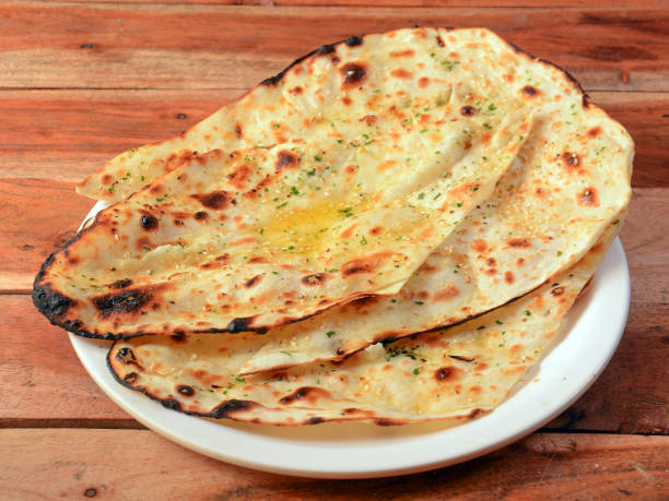 istock Butter naan, isolated over a rustic wooden background, selective focus 1292639033