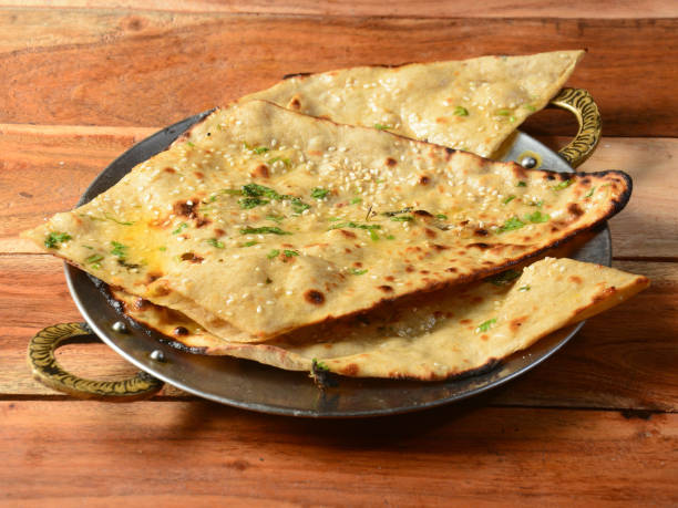 istock Garlic naan, isolated over a rustic wooden background, selective focus 1292639100
