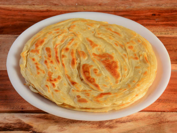 istock Kerala Paratha, a layered flat bread using wheat flour, popular dish in south India. isolated over a rustic wooden background, selective focus 1292639217