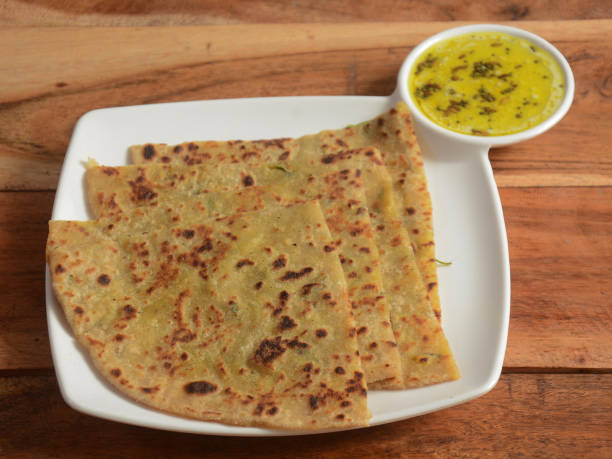 istock Aloo Paratha or Indian Potato stuffed Flatbread. Served with veg gravy. isolated over a rustic wooden background, selective focus 1292639285