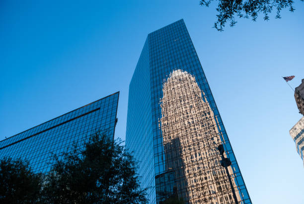 istock Large reflective skyscraper in downtown city reflecting the blue sky and another huge building in its glass windows 1292641371