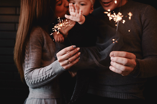 portrait of happy family, mom, dad and baby girl with sparklers and light. family in anticipation of Christmas. selective photo