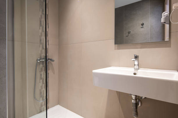 современный интерьер небольшой туалетной комнаты со стеклянным душем и белой прямоугольной раковиной, текстурированной мозаикой и сплошн - loft apartment bathroom mosaic tile стоковые фото и изображения