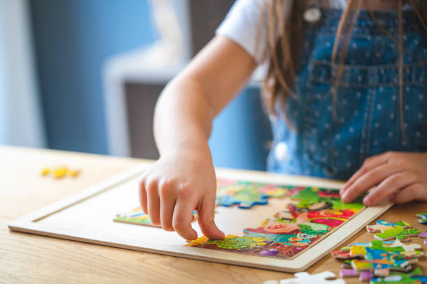 bambina che gioca con i puzzle a casa - puzzle foto e immagini stock