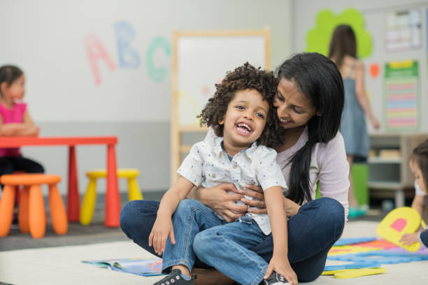 istock Mixed race boy sitting on preschool teacher's lap 1292652375
