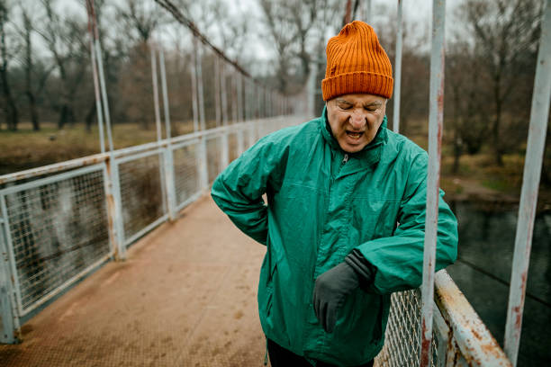 Senior man resting after jogging Senior man resting after jogging, he standing on a metal bridge guy-looking-over-fence stock pictures, royalty-free photos & images