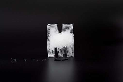 Natural ice cubes, melting on a black reflective surface.