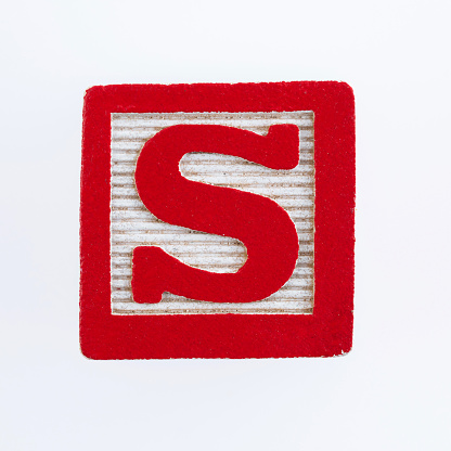 Wooden block with letter S on white background.