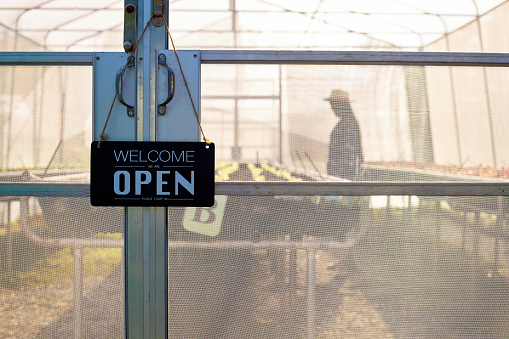 Greenhouse to grow organic vegetables with a welcome sign on the doorstep.