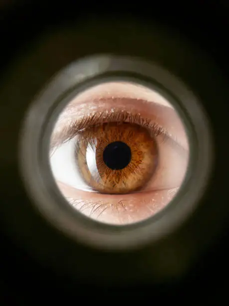 Close up shot of a eye looking through peephole to a cloudy sky