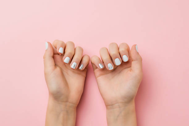 istock Well-groomed hands with stylish makeup on a light pink background. 1292665747