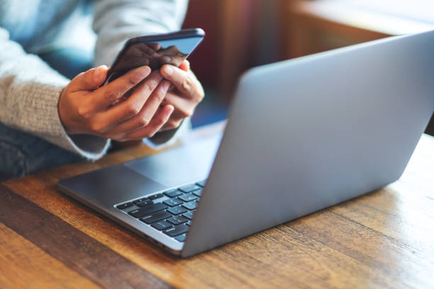 istock a woman holding and using mobile phone and laptop computer 1292666437