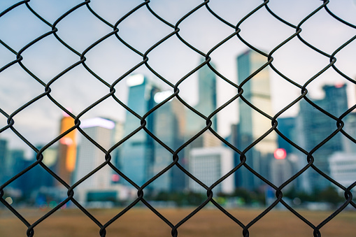 A skyline of skyscrapers behind a barbwire fence