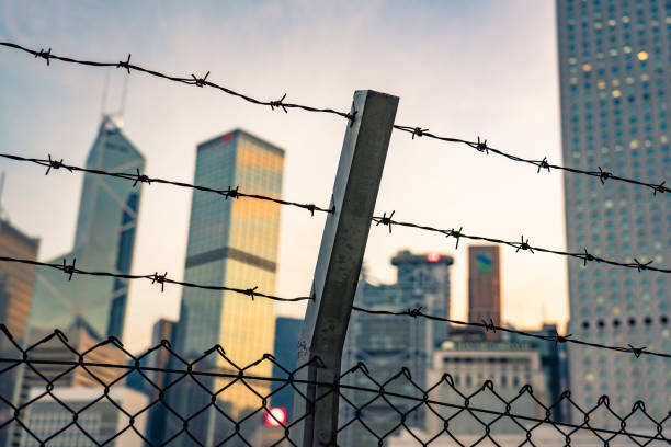 a skyline of skyscrapers behind a barbwire fence - razor wire imagens e fotografias de stock