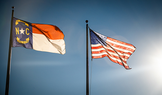 The state flag of North Carolina flies alongside the US flag.