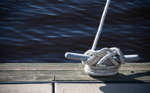 Tied Cleat Hitch A boat is anchored to a cleat hitch in a coastal harbor. anchored photos stock pictures, royalty-free photos & images