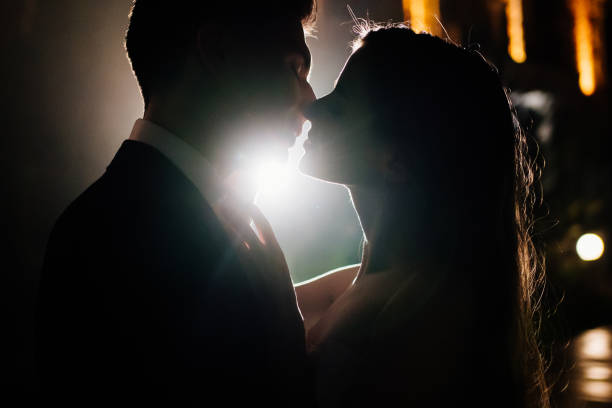 silhouettes of a man and a woman in love in the dark. romance. silhouettes of a man and a woman in love in the dark. romance. completion of the wedding celebration. kissing stock pictures, royalty-free photos & images