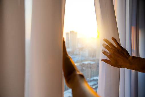 Hand opening curtain in the morning