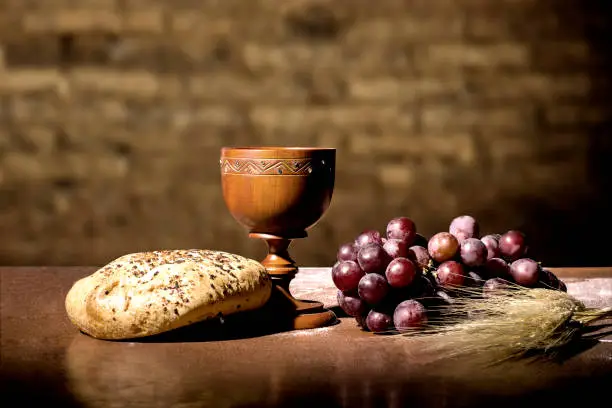 Photo of grapes, wheat, bread and wine in a wood table
