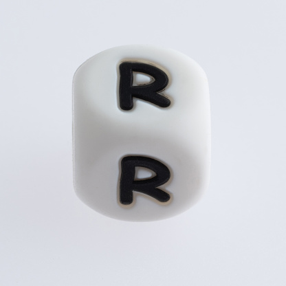 Dice with letter R on white background.