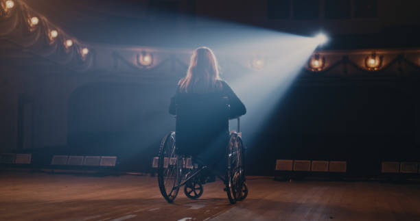Woman turning wheelchair round and leaving stage in end of performance in theater