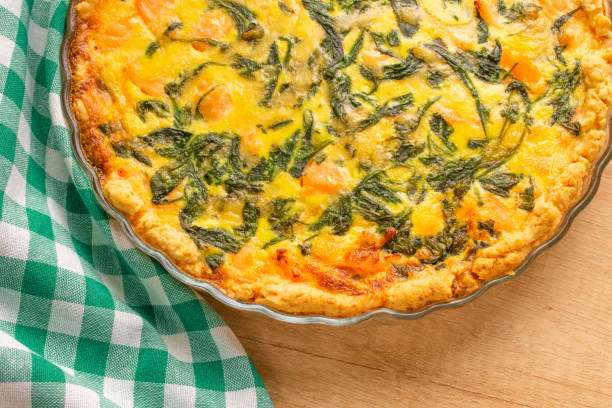 Seafood, salmon fish and baby spinach leaves quiche pie - homemade recipe pie on wooden table background with copy space, selective focus Close up view of salmon fish and baby spinach leaves quiche pie - homemade recipe pie on wooden table background with copy space. Selective focus fish pie stock pictures, royalty-free photos & images