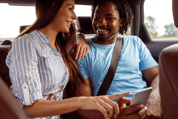 istock Couple having fun using smart phone while traveling in a car 1292697451