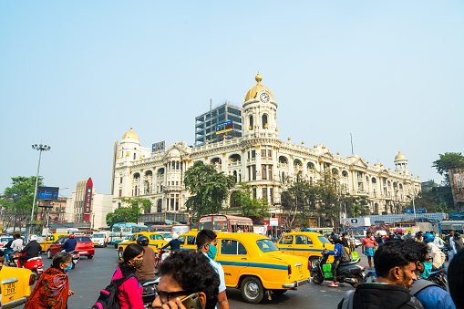 Kolkata, India, December 2020: Busy traffic of a notable city road near Esplanade with a yellow taxi at Chowringhee area Kolkata (calcutta) with Metropolitan colonial heritage building.