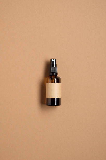 garrafa de spray de vidro âmbar com maquete de rótulo em branco no fundo marrom. design de embalagens de cosméticos naturais. flat lay, vista para cima. - amber bottle - fotografias e filmes do acervo