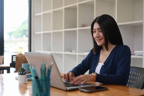 istock Young female designer working on freelance is browsing information for project on laptop at creative workstation. 1292702906