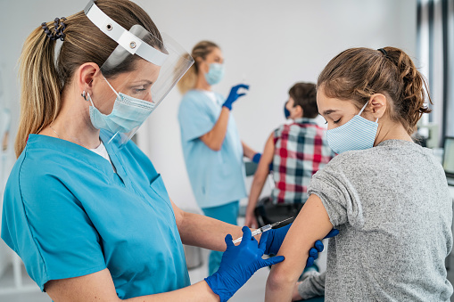Doctor vacunando a la chica. Inyección de la vacuna COVID-19 en el brazo del paciente photo