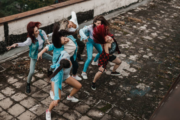 Dance group dancing on the top of the building Group of young street-styled urban women dancing on the top of a building in the city on an autumn day dance troupe stock pictures, royalty-free photos & images