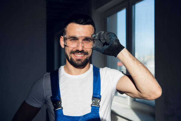 Builder in blue overalls and goggles smiling stock photo
