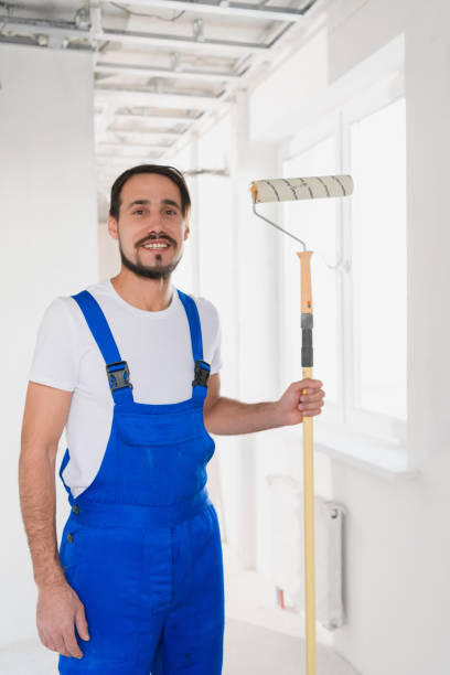 istock A bearded painter in a blue overalls holds a roller in his hand and poses at the camera 1292710043