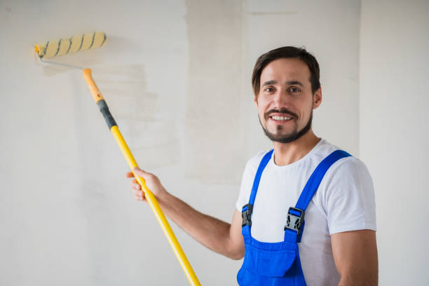 istock Smiling painter stands near the wall and holds a roller in his hands 1292710049