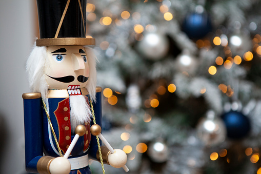 Soldier nutcracker statue in front of decorated Christmas tree with blurred lights