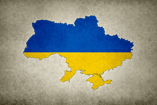 Grunge map of Ukraine with its flag printed within its border on an old paper.