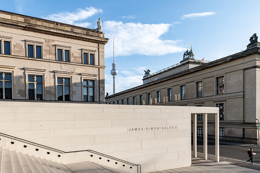 Berlin, Germany - December 20, 2020: stairs of the James Simon Gallery in front of museum buildings and Berlin Tv Tower under blue december sky