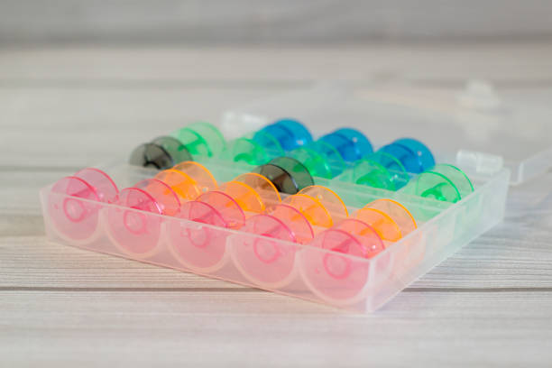 istock Bright colored plastic bobbins for a sewing machine on a light wooden background close up, in organizer 1292715557