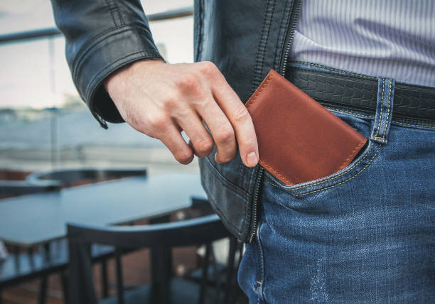Men's hand wallet in the pocket The man pulls a brown leather wallet out of his jeans pocket wallet photos stock pictures, royalty-free photos & images