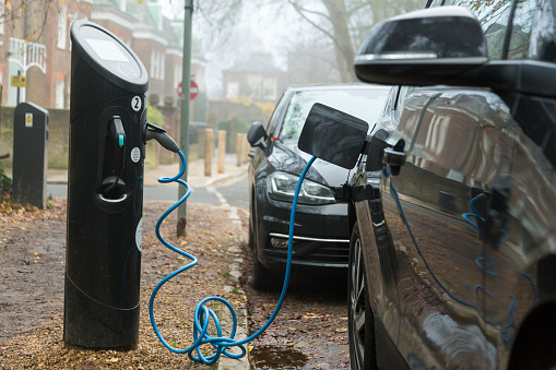 London, UK - 7 December, 2020: Close up color image depicting a modern electric car being charged at a charging point on a residential street in London, UK.