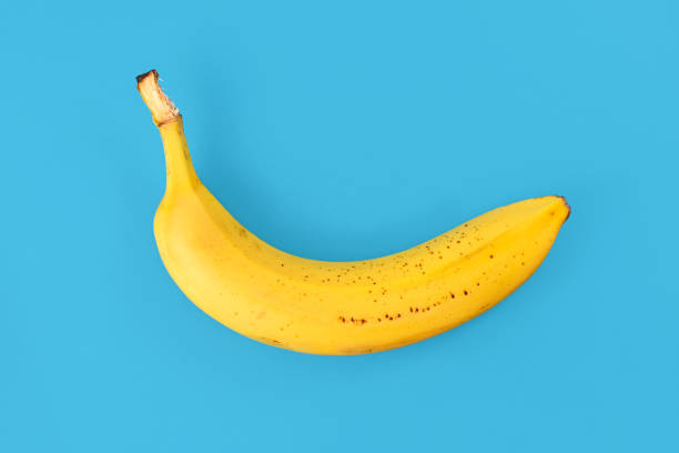 istock Single ripe banana fruit with peel on blue background 1292720203