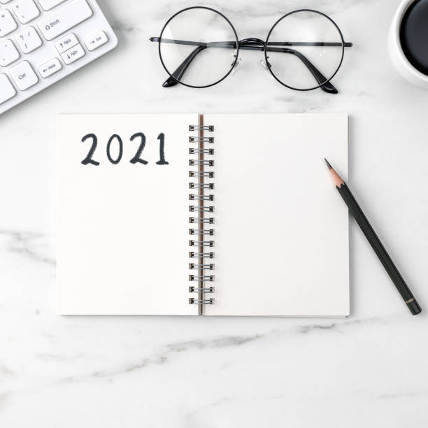 istock Top view of office table desk 2021 Goal work concept on bright marble white background. 1292721239