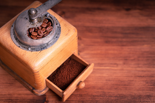 Close up of barista pouring boiling water from a metal teapot into a glass carafe to make a pour over coffee at a coffee shop.