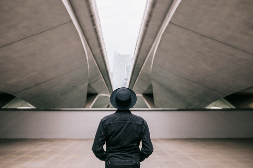 Rear view of man standing under the bridge on a dark day