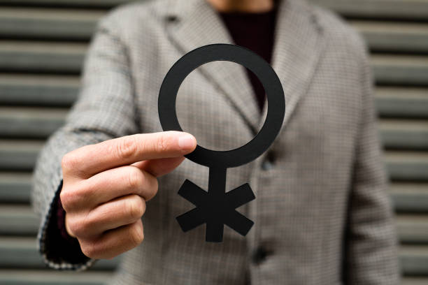 person showing a non-binary gender symbol closeup of a young caucasian person standing on the street, wearing a coat, showing a non-binary gender gender fluid photos stock pictures, royalty-free photos & images