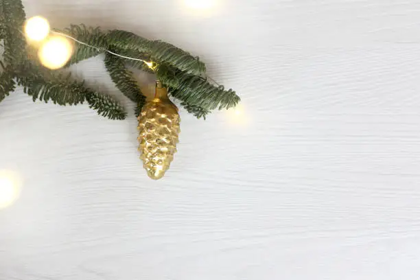 glass golden Christmas tree toy and fir branch with garland lights