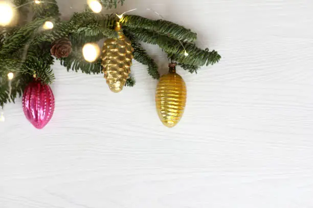 three glass Christmas tree toys on a fir branch with garland lights